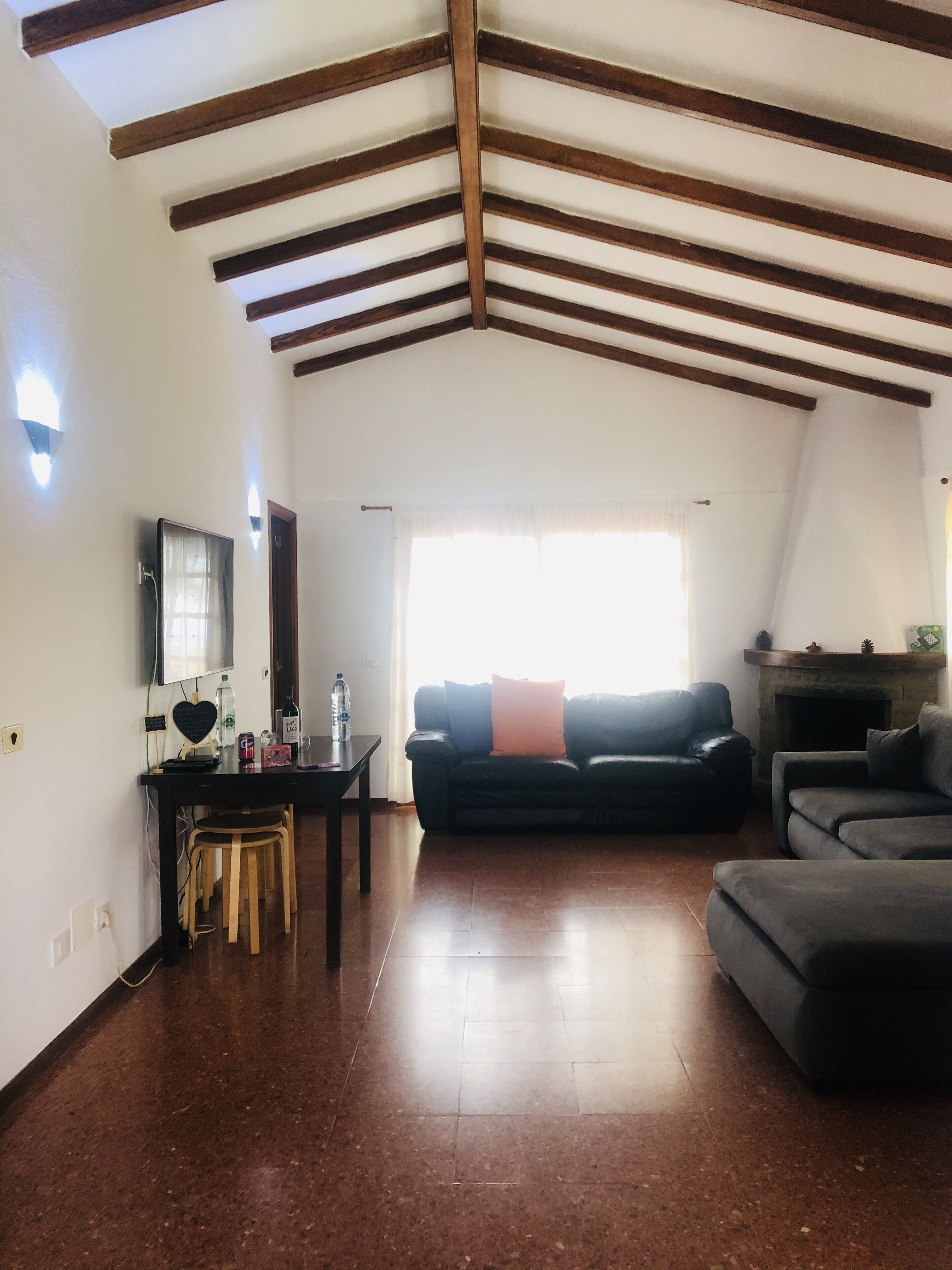A spacious living room with a high ceiling, a fireplace, and a large window.