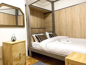 Un dormitorio con una cama litera de madera, una mesita de noche con un farol y un aparador de madera.