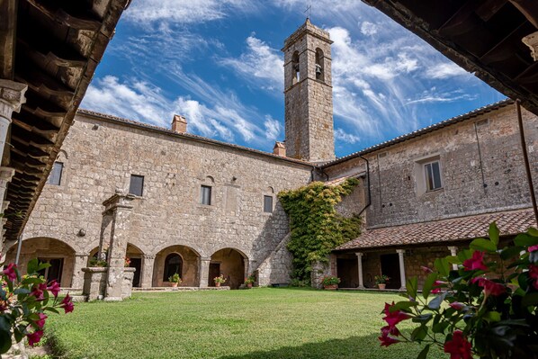 Un patio con edificios de piedra, una torre campanario y cielo despejado.