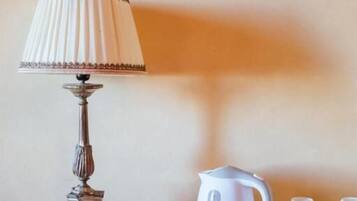 Un tavolo di legno con una lampada, un bollitore, tazze e un cesto.