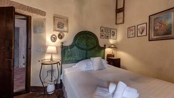 A hotel room with a bed, a nightstand, a lamp, and a door leading to a corridor.