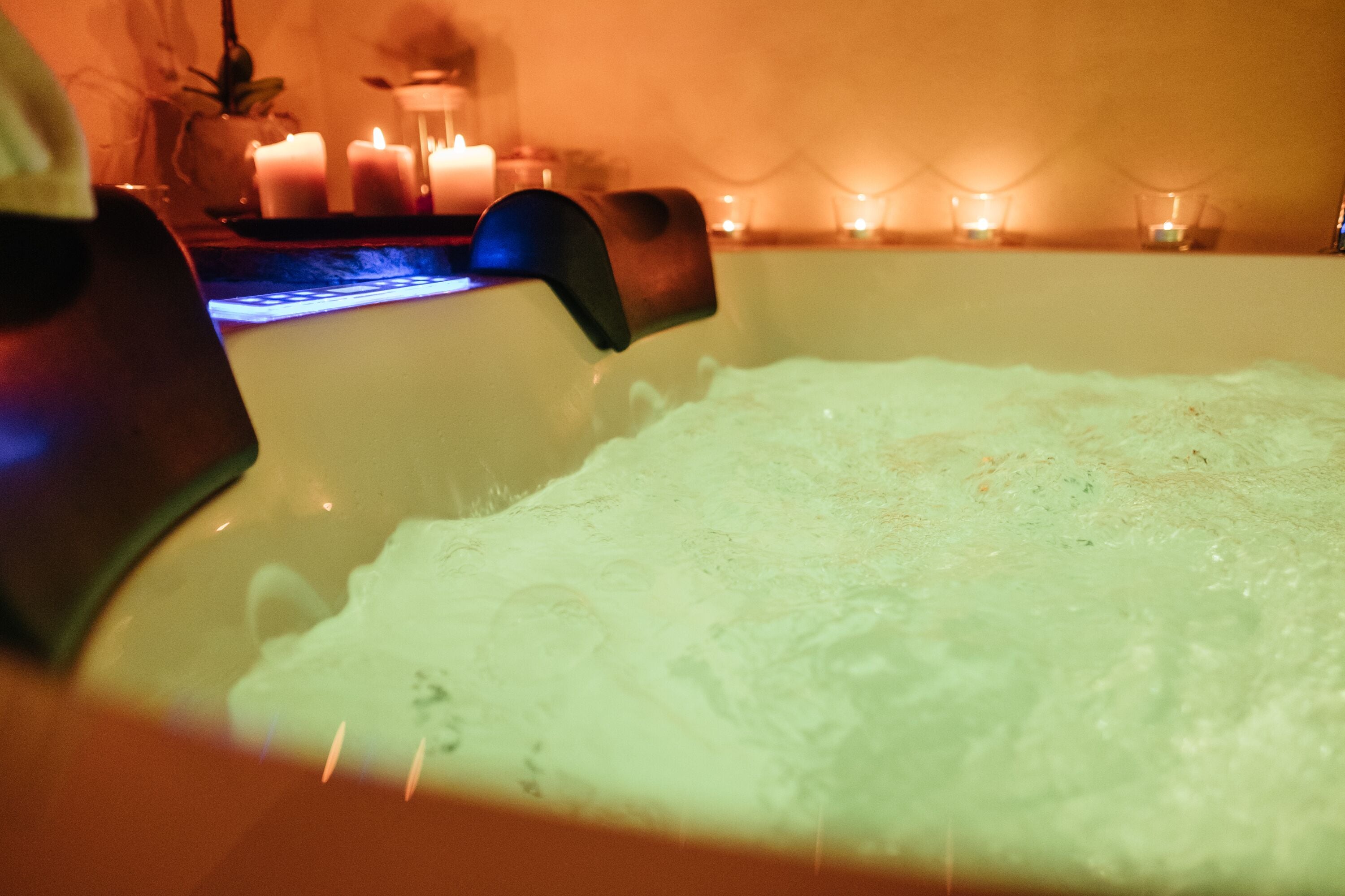 Eine Badewanne mit fließendem Wasser, umgeben von Kerzen und einer warmen Atmosphäre.