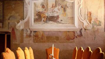 Un comedor con una larga mesa de madera, sillas ornamentadas y un cuadro sobre la mesa.