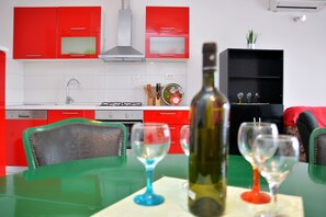 Uma cozinha moderna com armários vermelhos, exaustor de aço inoxidável e uma estante preta.