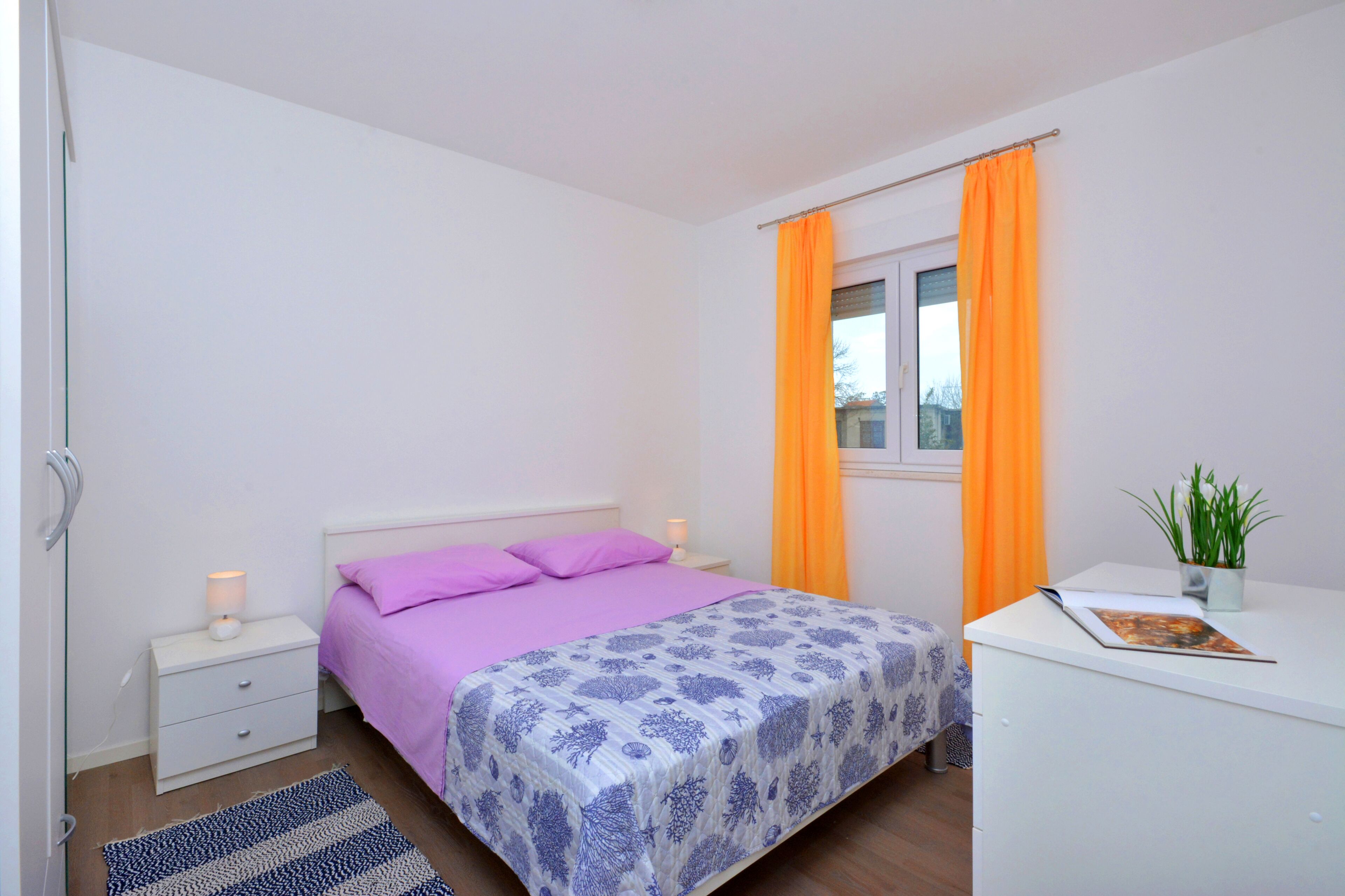 Camera da letto con un letto, comodino, scrivania e finestra con tende.