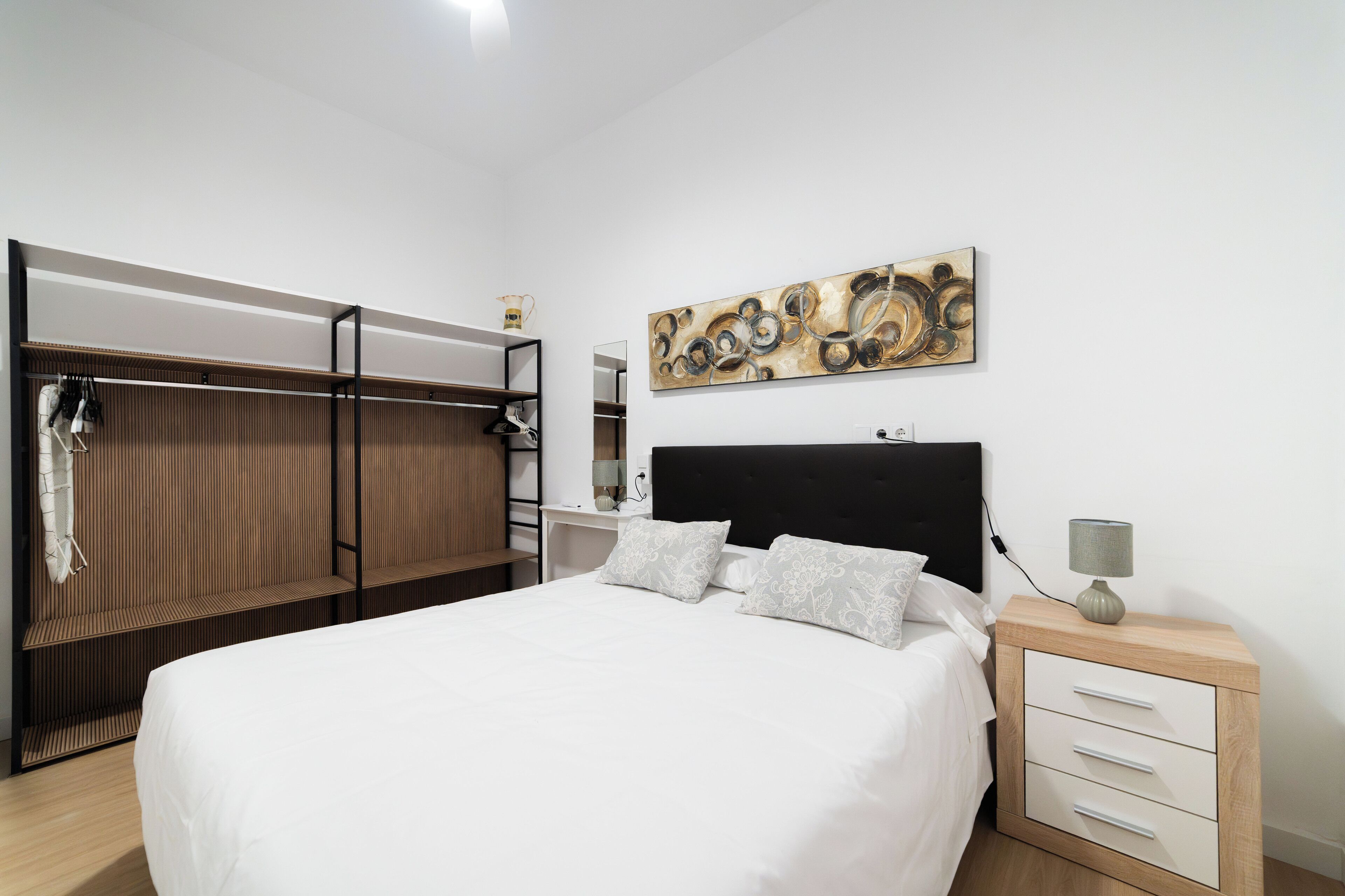 Ein Schlafzimmer mit einem Bett, einem Nachttisch, einem Wandbild und einem Kleiderschrank.