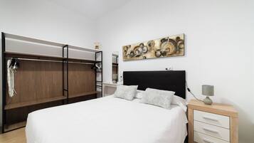 Ein Schlafzimmer mit einem Bett, einem Nachttisch, einem Wandbild und einem Kleiderschrank.