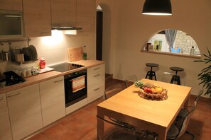 A modern kitchen with a wooden countertop, built-in oven, and a dining area with a table set for two. - Apartments Maric (Pula)