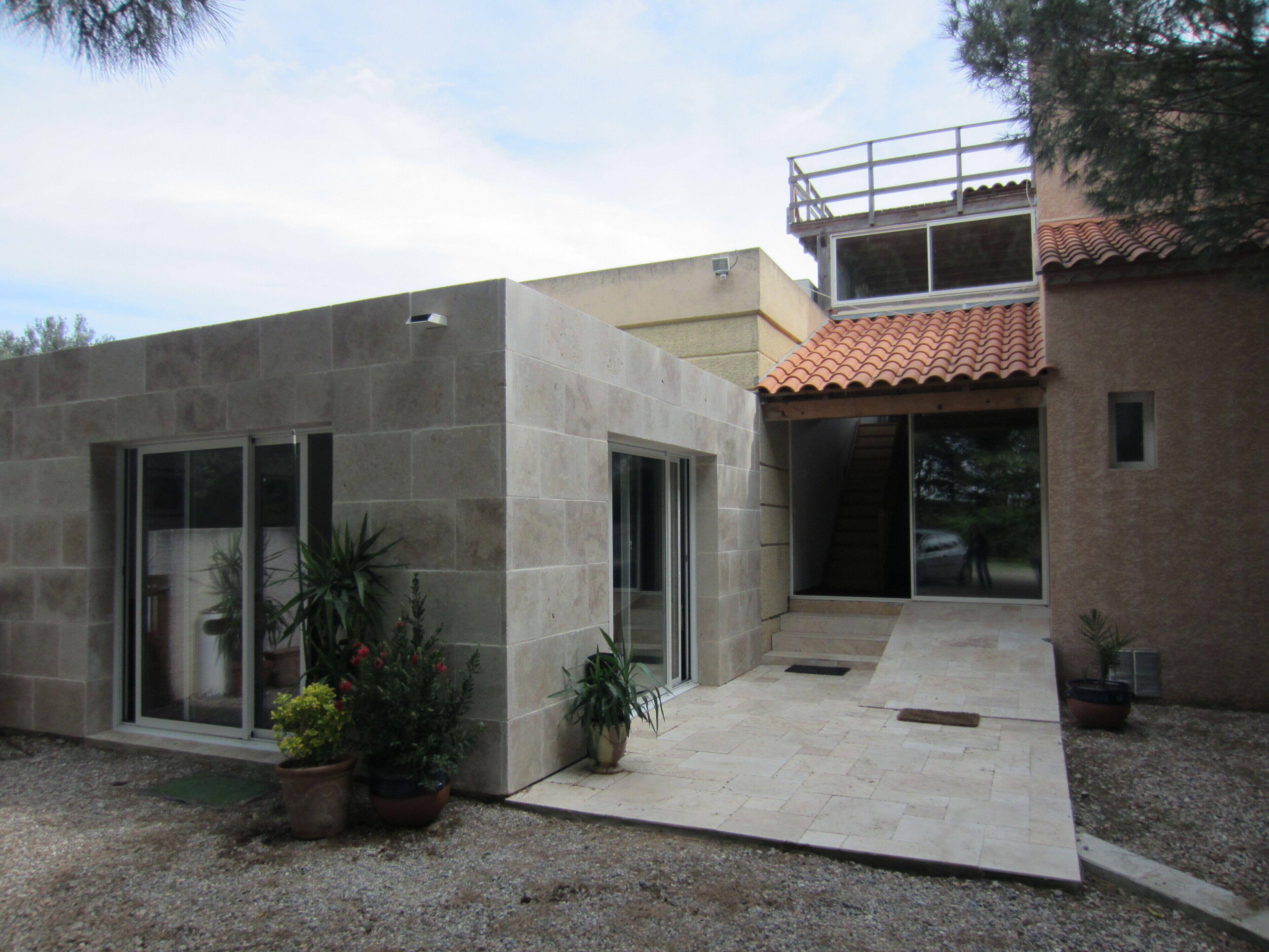 A modern house with a flat roof, large windows, and a small balcony.