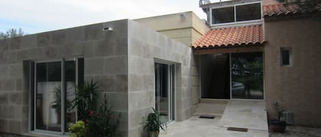 A modern house with a flat roof, large windows, and a small balcony.