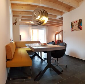Un salon moderne avec un plafond en bois, un canapé, une table à manger et un tableau accroché au mur.
