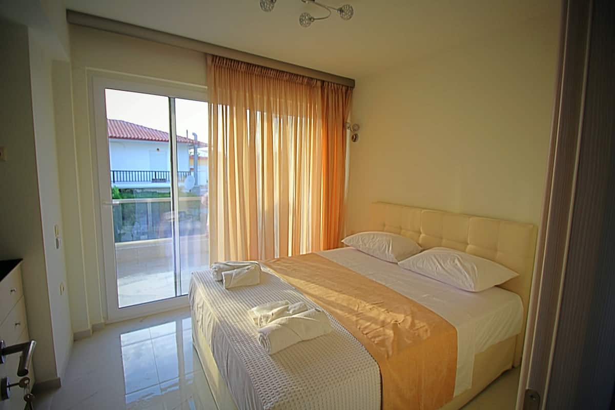 A hotel room with a bed, a bathroom, and a sliding glass door leading to a balcony.