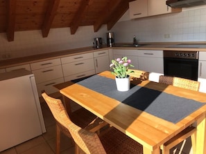 Eine Küche mit Holzausstattung, einem Herd und einem Esstisch mit Stühlen.