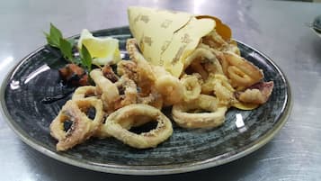 A plate of fried calamari with lemon wedges and a wedge of lemon on a ceramic plate.