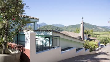 Un edificio con fachada blanca, un balcón y vistas a montañas.