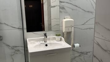 A bathroom with a white sink, mirror, and marble-tiled walls.