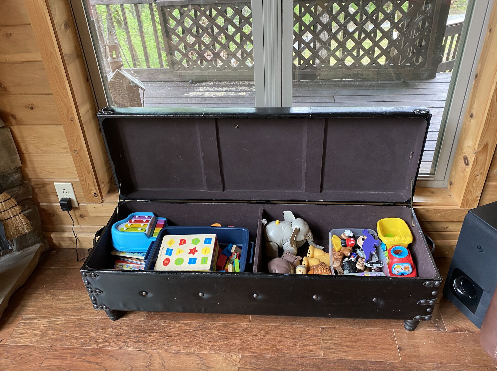 A suitcase with compartments containing toys and a broom.
