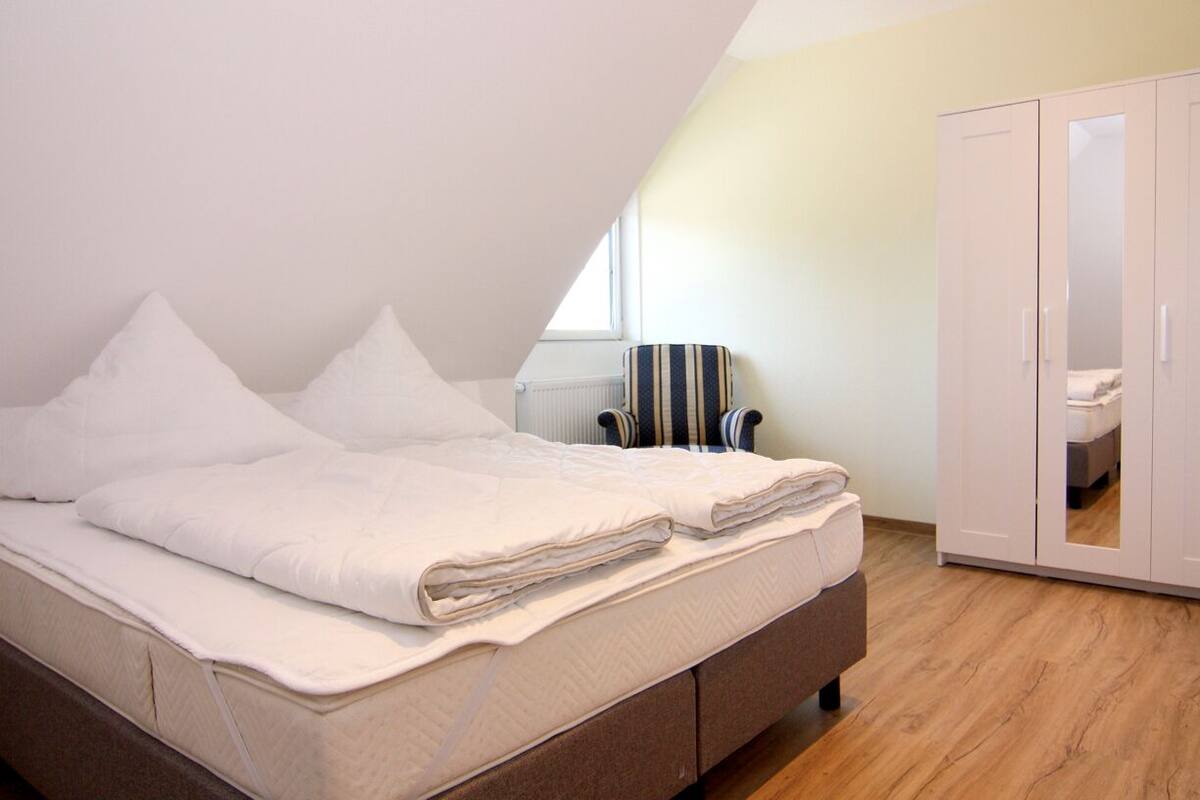 A bedroom with a bed, a chair, and a wardrobe.