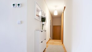 A hallway with a white cabinet, a thermostat, and a door at the end. - Apartment - OPO 31 (Porto)