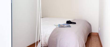 A small, neatly arranged bedroom with a single bed, a camera, and a book on the bed.