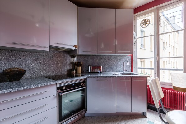 Eine Küche mit Granit Arbeitsplatte, Edelstahlgeräten und einem Fenster mit Blick auf Gebäude.