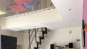 En stue med en moderne trappe, et fladskærms-tv, en hvid sofa og et skab med glashylder.