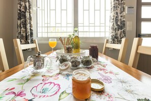 Uma mesa de jantar com toalha florida, vários potes, uma garrafa e um copo de suco de laranja.