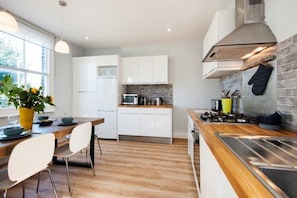 A modern kitchen with white cabinets, a wooden countertop, and a stove.