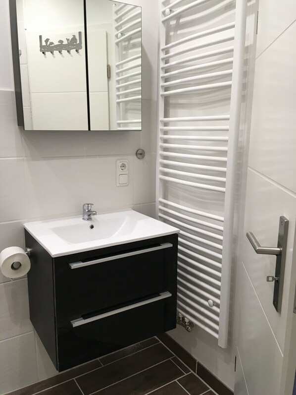 A bathroom with a white sink, a mirror, and a towel rack. - Stranded robber Strelasund in Stralsund (Stralsund)