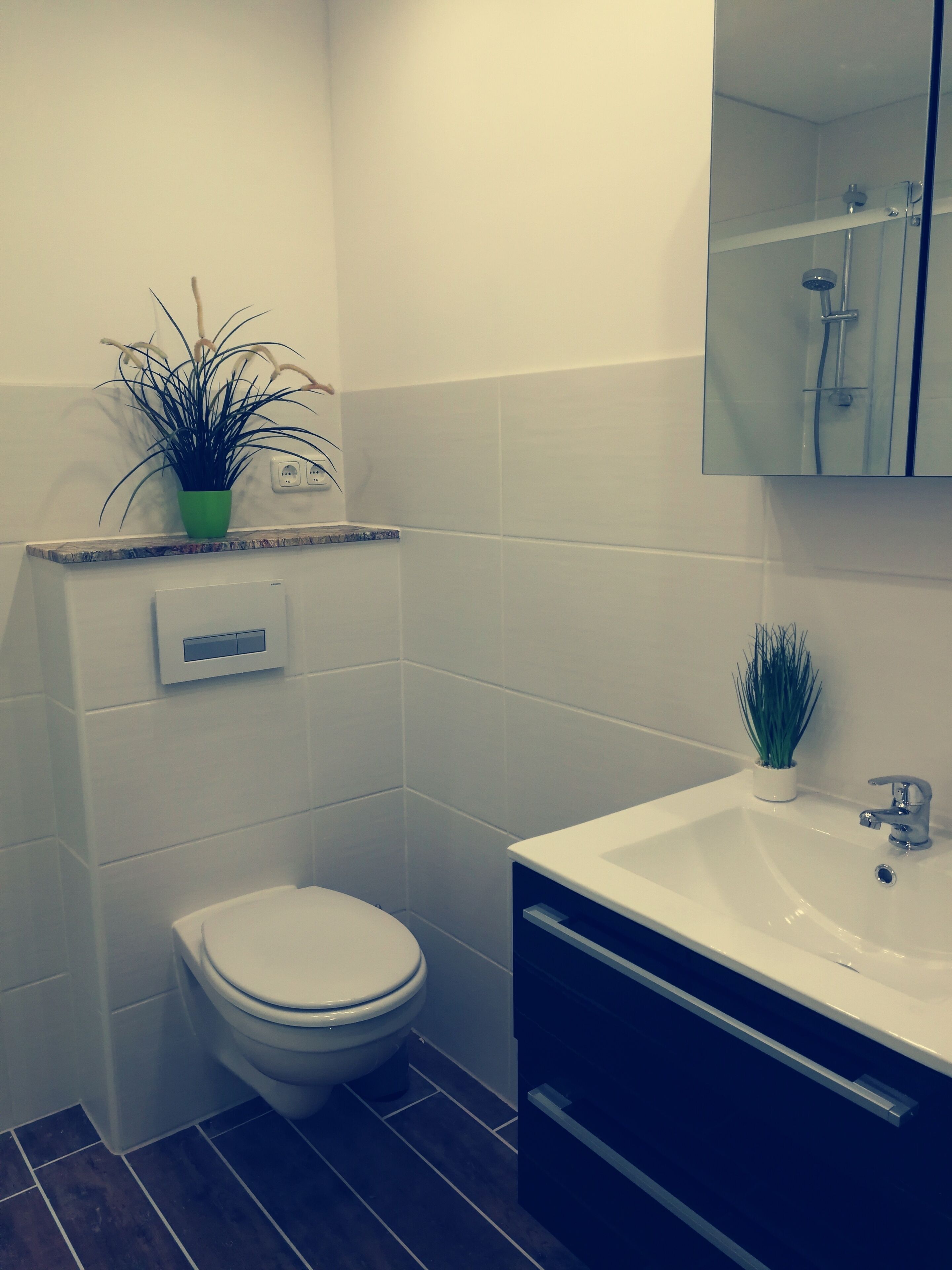 Een moderne badkamer met toilet, wastafel en een spiegel boven de wastafel.