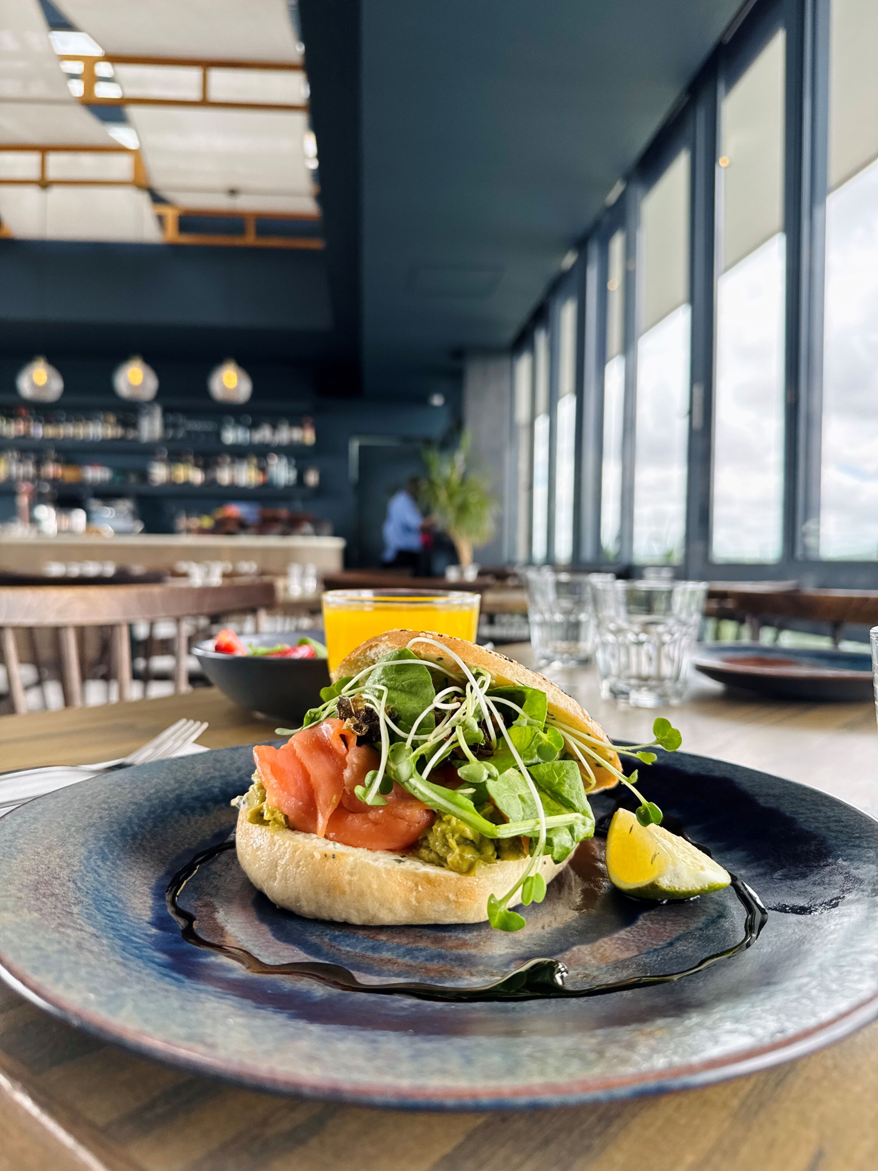 A sandwich on a plate with a drink in the background.