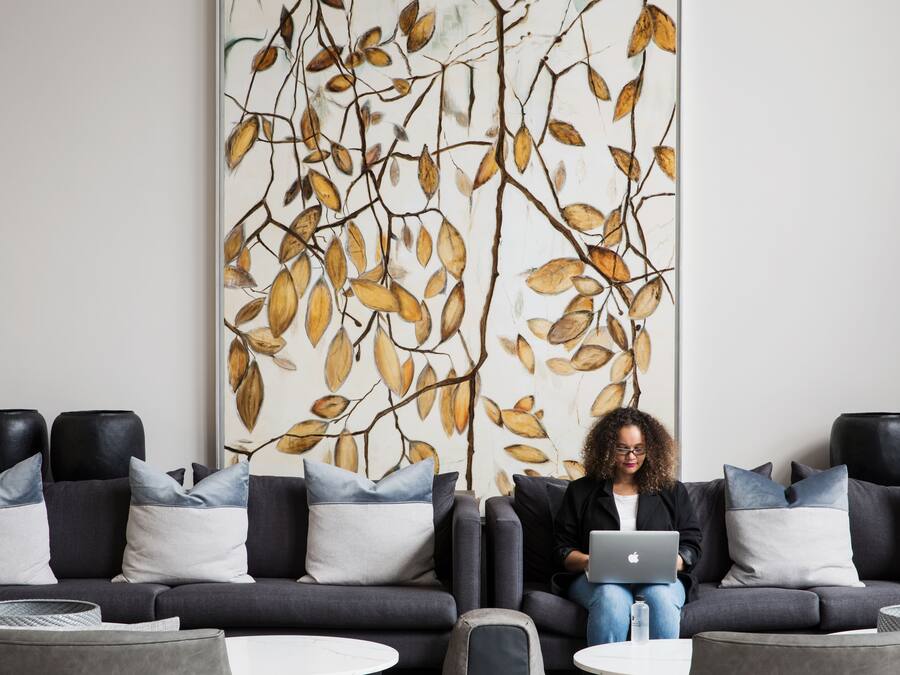 A modern living room with a sofa, coffee table, and a large wall art piece.