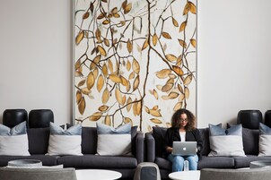 A modern living room with a sofa, coffee table, and a large wall art piece.