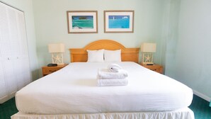 Ein Hotelzimmer mit einem großen Bett, zwei Nachttischen, einem Holzkopfteil, weißer Bettwäsche und zwei gerahmten Bildern an der Wand.