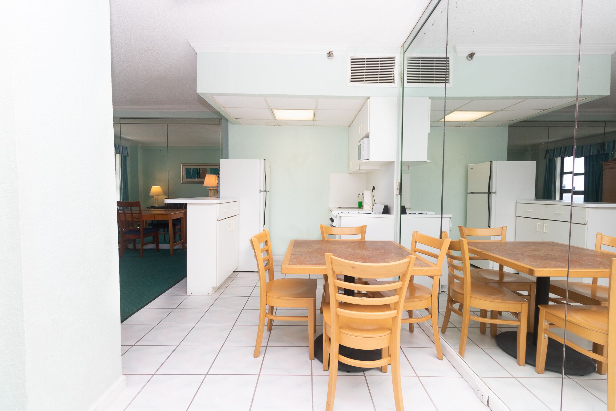 Une cuisine compacte avec un coin repas, comprenant un petit îlot central, des meubles blancs et un four à micro-ondes.