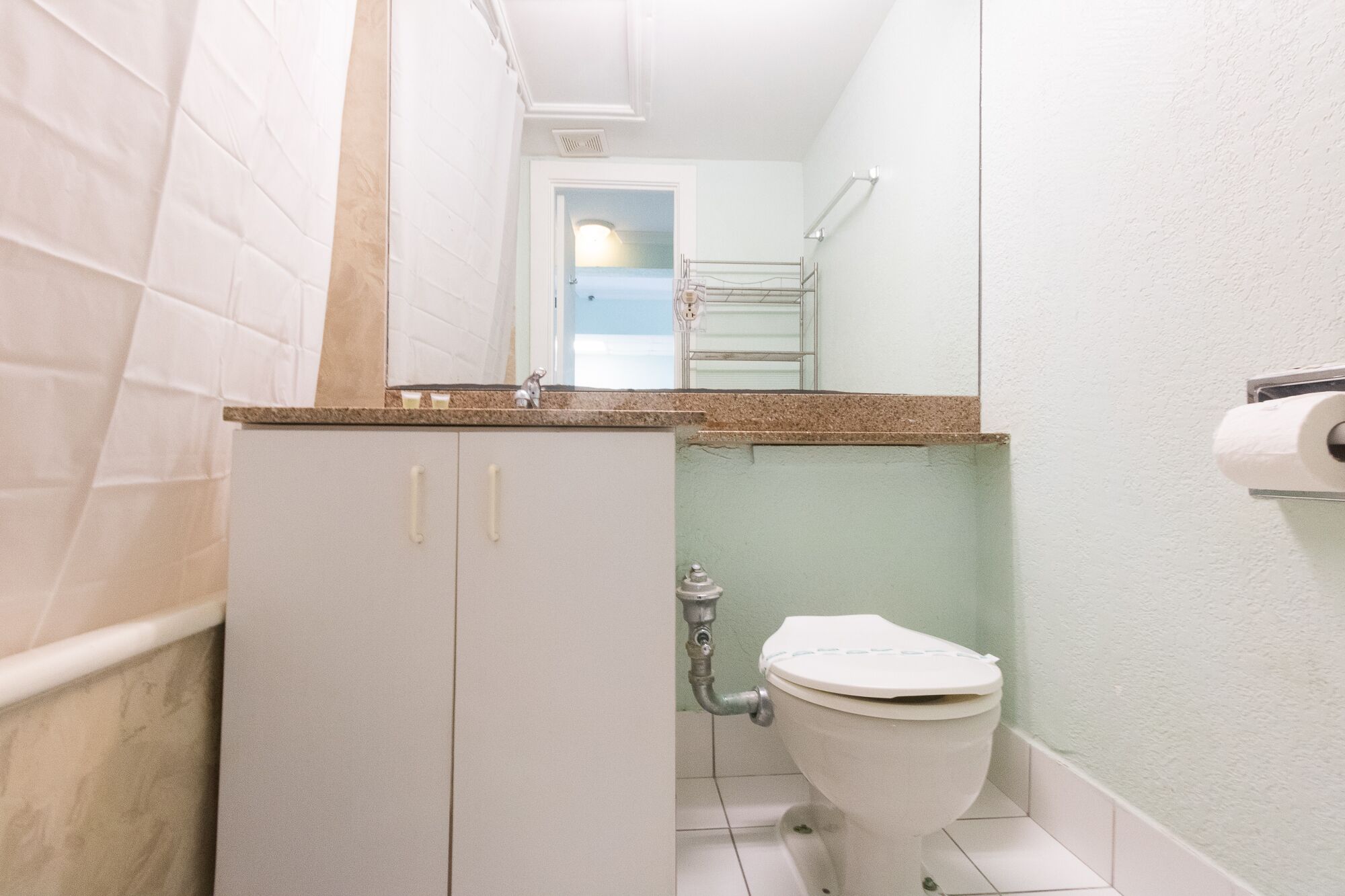 Een kleine badkamer met toilet, een wastafel met spiegel en een handdoekhouder.