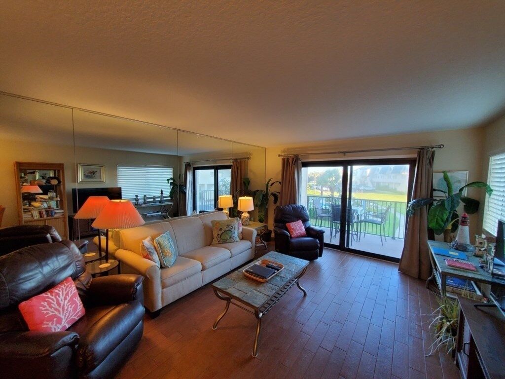 A living room with a sofa, armchairs, a coffee table, and a balcony with a view.