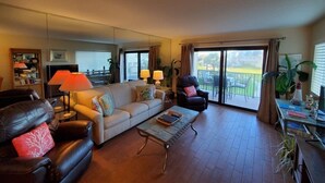 Un salon comprenant un canapé, des fauteuils, une table basse et un balcon avec vue.