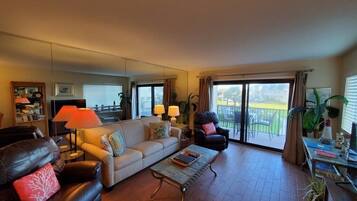 A living room with a sofa, armchairs, a coffee table, and a balcony with a view.