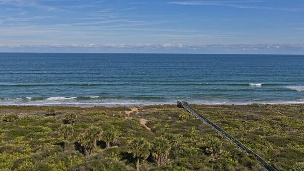 A coastal landscape with a clear sky, ocean waves, and a pathway leading to the beach. - Surf Club I, 1405 2 Bedroom Condo by RedAwning (Palm Coast)