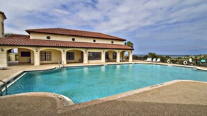 A swimming pool with a covered area, lounge chairs, and a view of the ocean. - Surf Club I, 1405 2 Bedroom Condo by RedAwning (Palm Coast)
