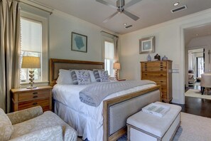 Une chambre à coucher avec un grand lit, des tables de chevet, une commode et un ventilateur de plafond.