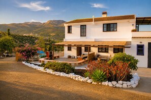 A two-story house with a patio, outdoor seating, and a view of mountains.