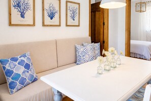 Ein Zimmer mit einem beigen Sofa, einem weißen Tisch und drei gerahmten Pflanzenbildern an der Wand.