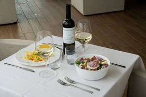 Una mesa dispuesta con una botella de vino, copas, platos de comida y cubiertos.
