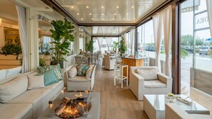 Un espace intérieur vaste et accueillant, doté d’un foyer, de coins salon et de grandes fenêtres offrant une vue sur l’extérieur.