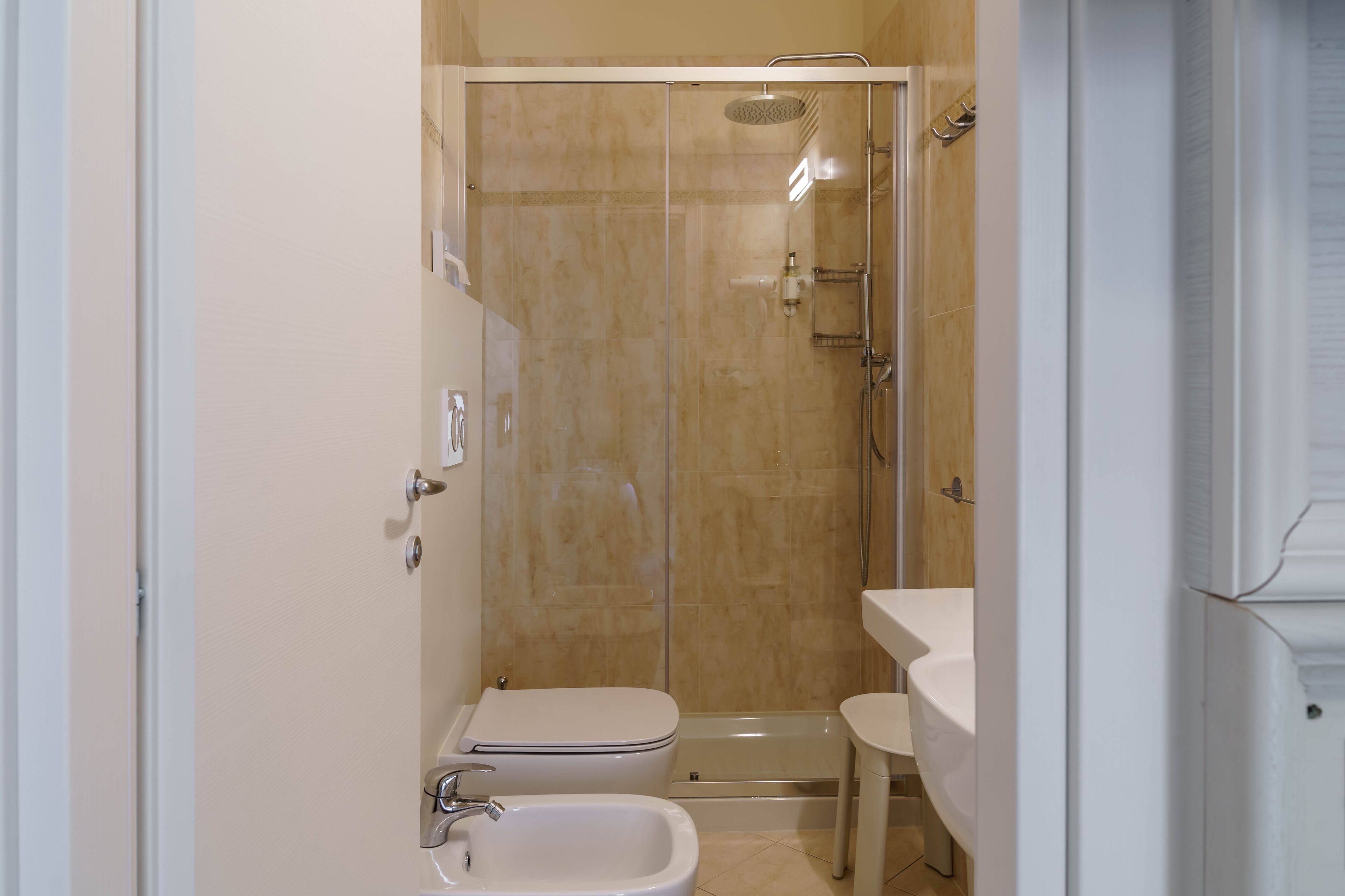 A small, modern bathroom with a glass-enclosed shower, a toilet, and a sink.