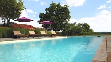 Una piscina al aire libre de temporada, una piscina natural, sombrillas