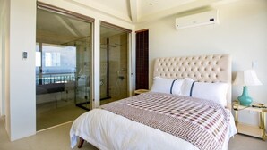 A bedroom with a large bed, a glass door leading to a balcony, a wall-mounted air conditioner, and a bedside lamp. - Navy Hill Resort (Saipan)