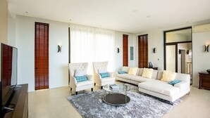 A modern living room with a sofa, two armchairs, a coffee table, and a TV. - Navy Hill Resort (Saipan)